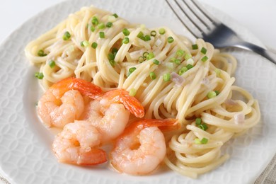 Photo of Delicious pasta with shrimps and green onions on plate, closeup