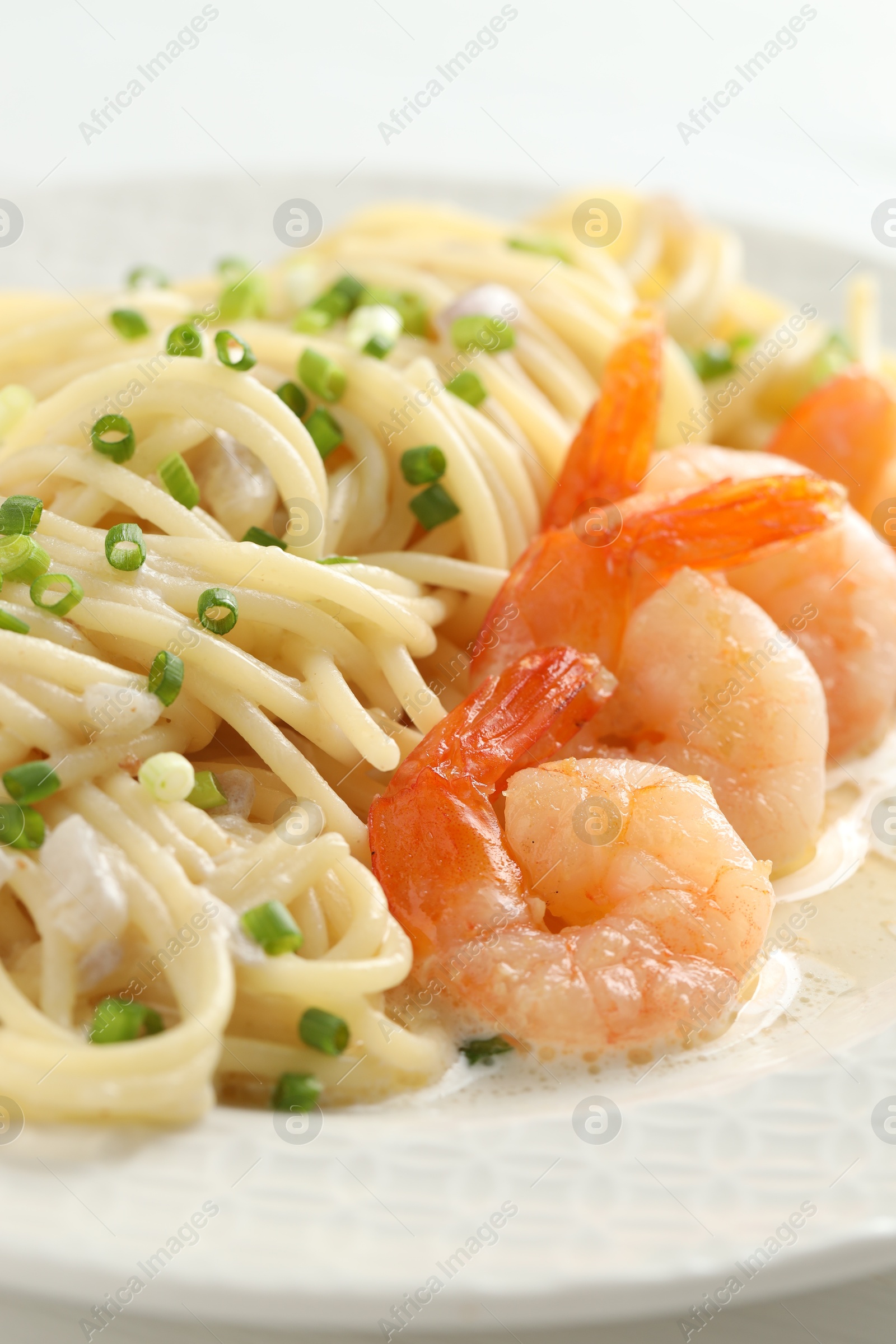 Photo of Delicious pasta with shrimps and green onions on plate, closeup