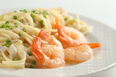 Delicious pasta with shrimps and green onions on table, closeup