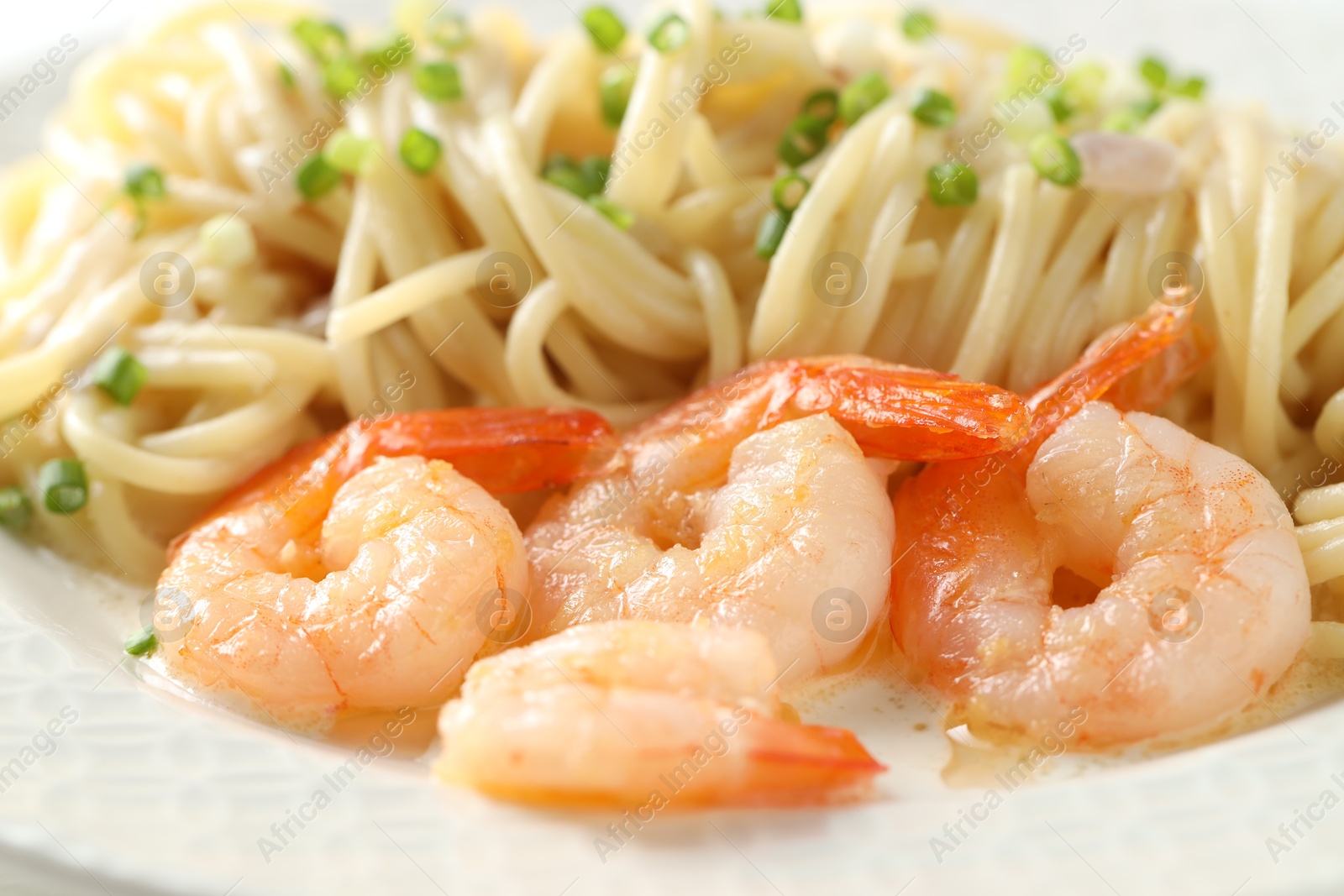 Photo of Delicious pasta with shrimps and green onions on plate, closeup