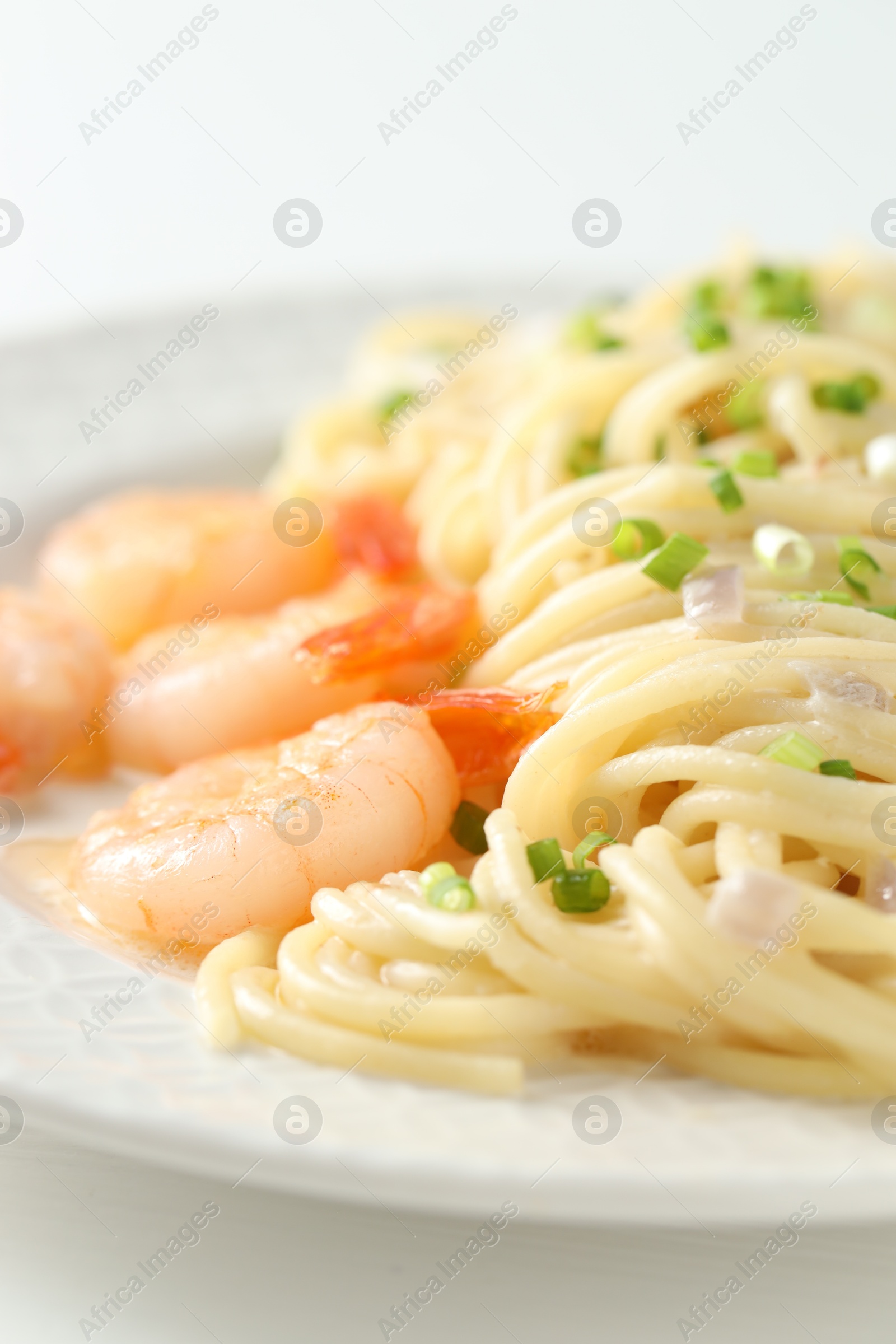 Photo of Delicious pasta with shrimps and green onions on white table, closeup