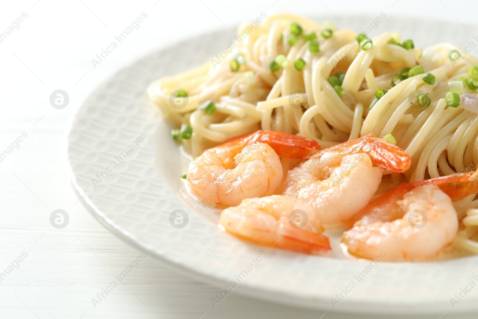 Photo of Delicious pasta with shrimps and green onions on white wooden table, closeup