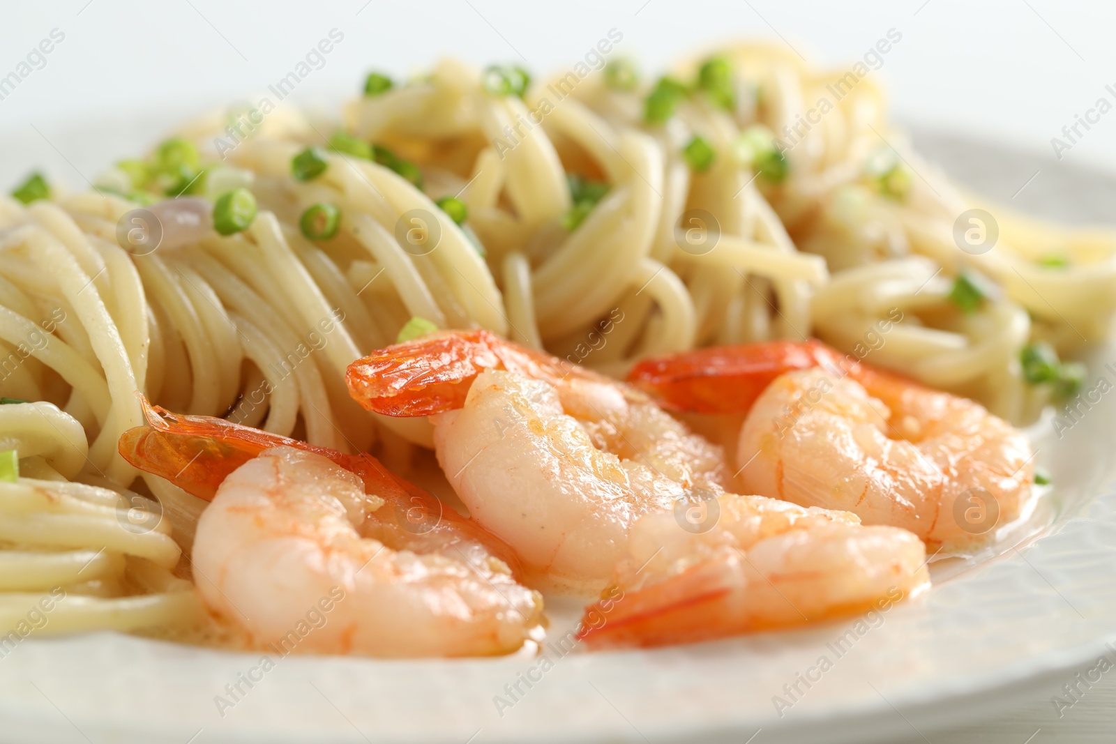 Photo of Delicious pasta with shrimps and green onions on plate, closeup