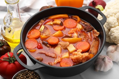 Tasty homemade stew with vegetables on white tiled table, closeup