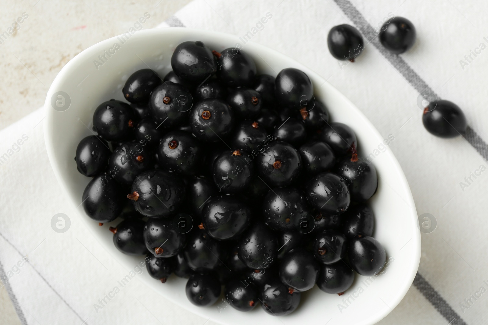 Photo of Ripe black currants in bowl on light table, top view