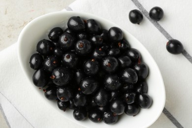 Ripe black currants in bowl on light table, top view