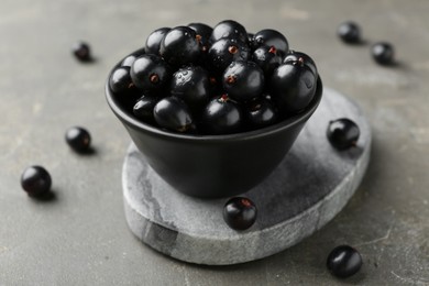 Photo of Ripe black currants in bowl on grey table