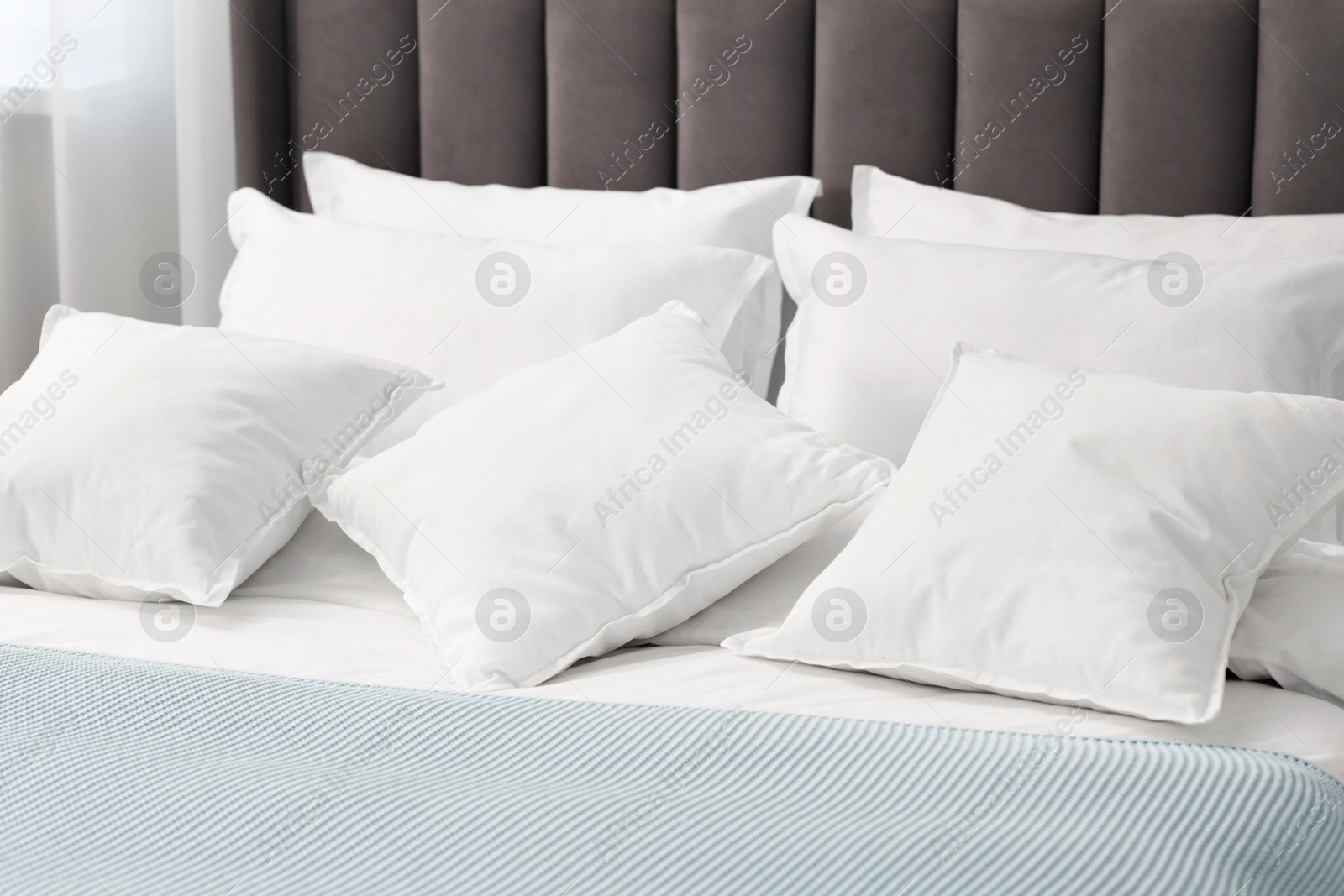 Photo of Many soft pillows on bed at home