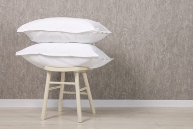 Photo of Many soft pillows on chair near grey wall. Space for text