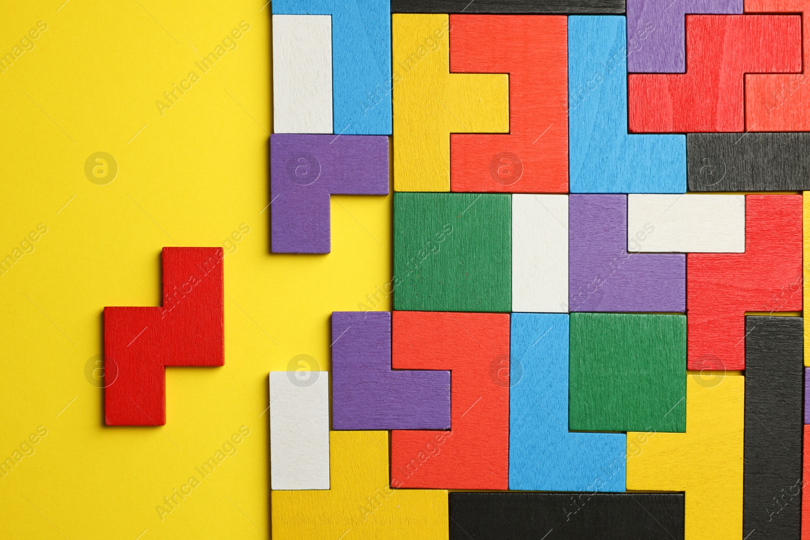 Photo of Colorful wooden puzzle pieces on yellow background, top view