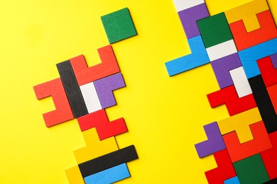 Photo of Colorful wooden puzzle pieces on yellow background, top view