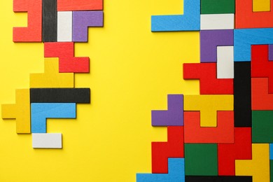 Photo of Colorful wooden puzzle pieces on yellow background, top view