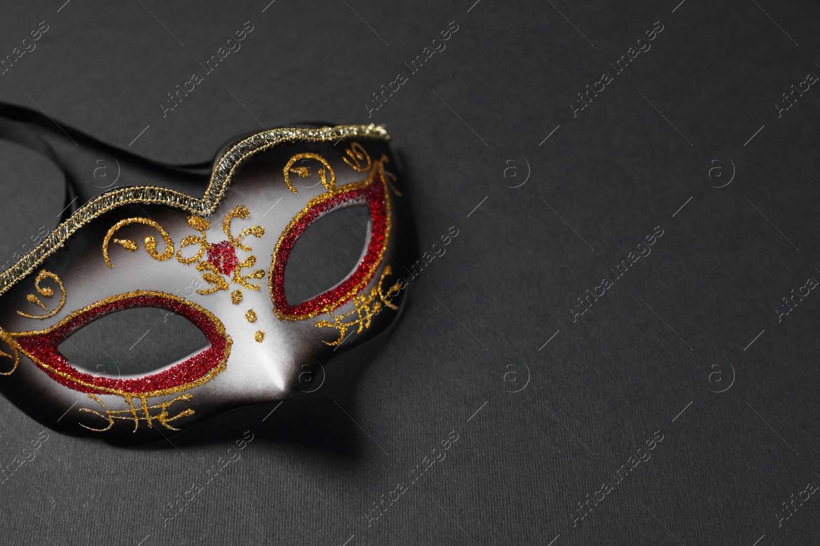 Photo of Beautiful carnival mask on black background, space for text