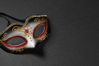 Photo of Beautiful carnival mask on black background, space for text