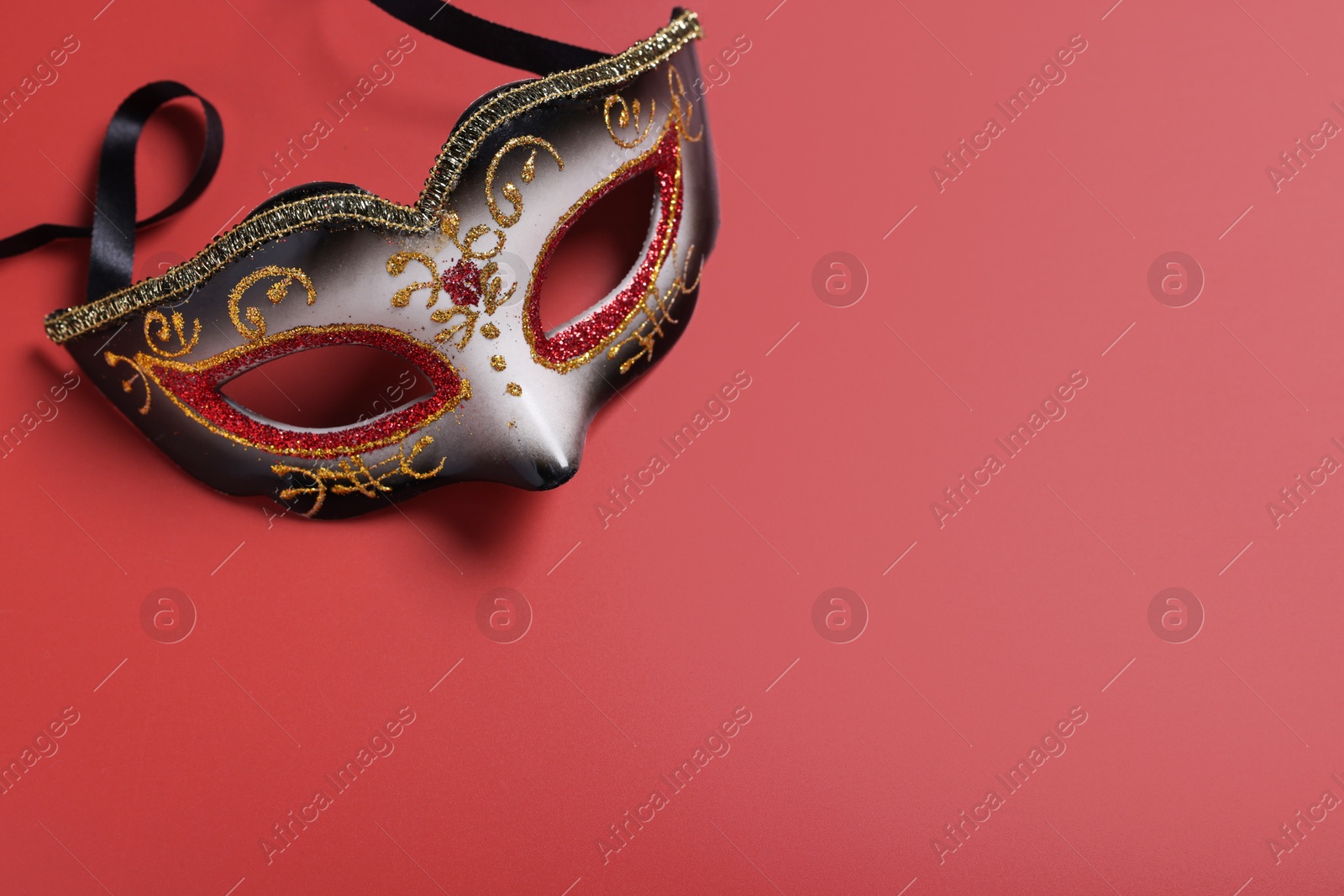 Photo of Beautiful carnival mask on red background, top view. Space for text