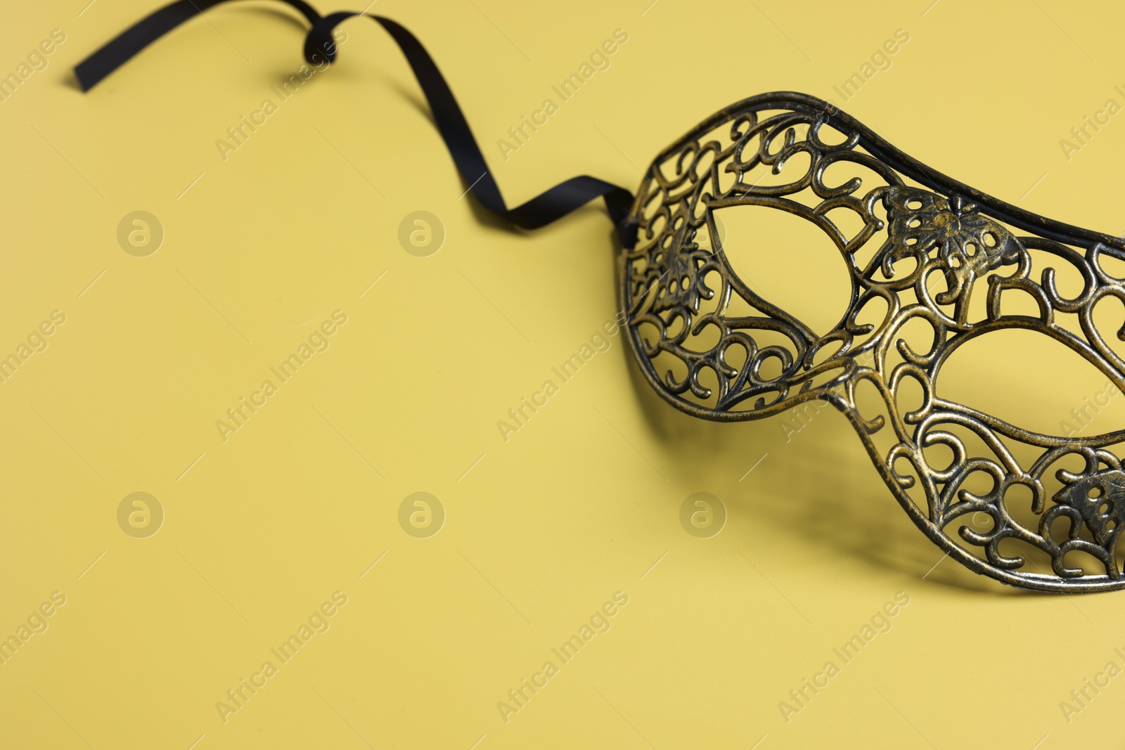 Photo of Beautiful carnival mask on yellow background, space for text