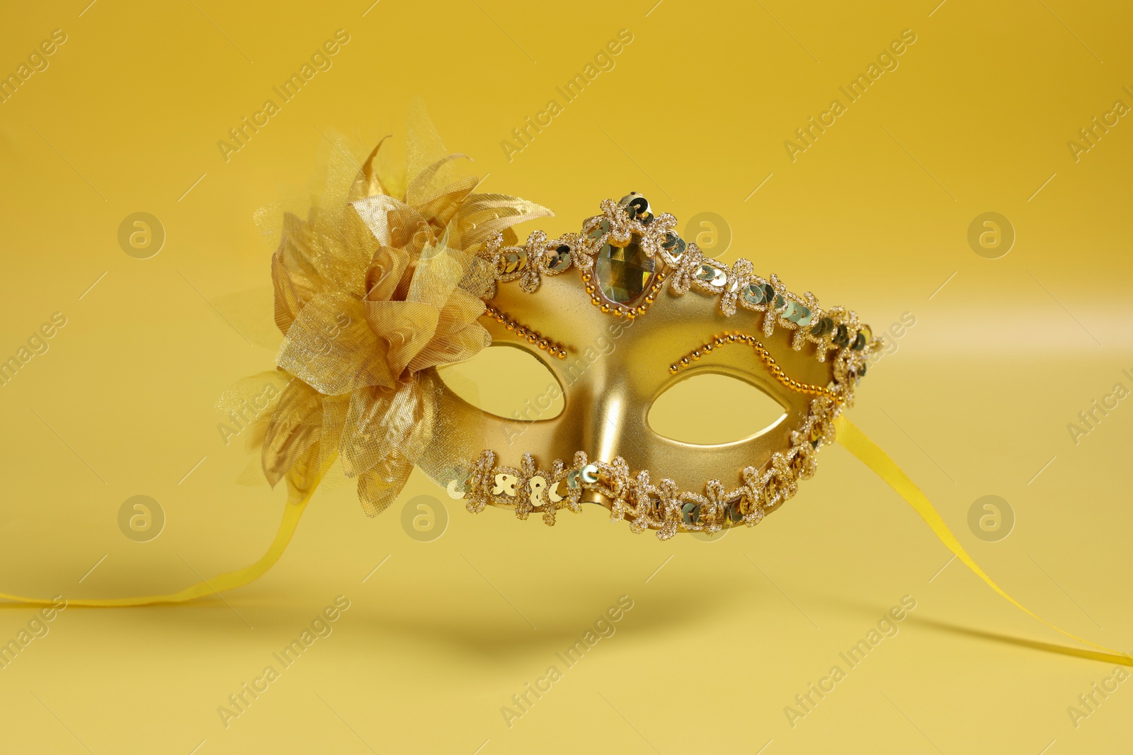 Photo of Beautiful carnival mask in air on yellow background