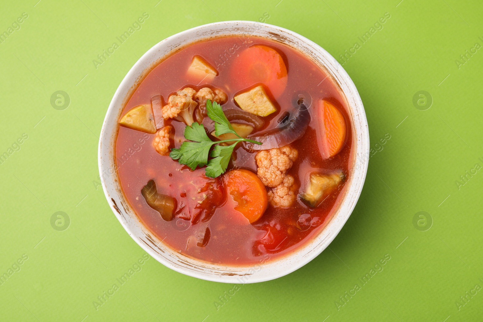 Photo of Delicious homemade stew in bowl on green background, top view