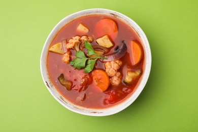 Photo of Delicious homemade stew in bowl on green background, top view