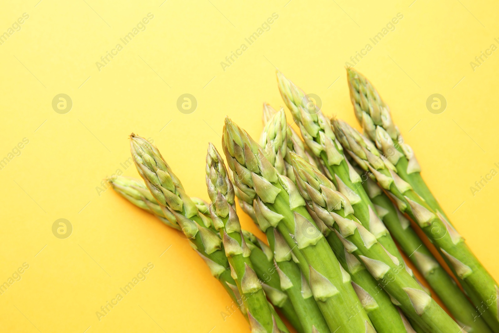 Photo of Fresh green asparagus stems on orange table, top view