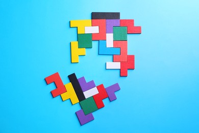 Photo of Colorful wooden puzzle pieces on light blue background, top view