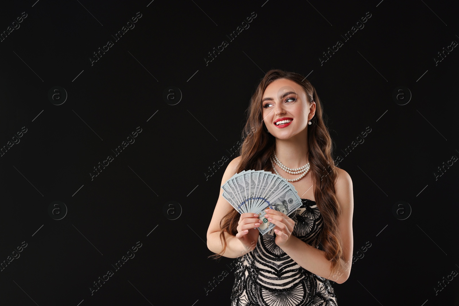 Photo of Smiling woman with dollar banknotes on black background. Space for text