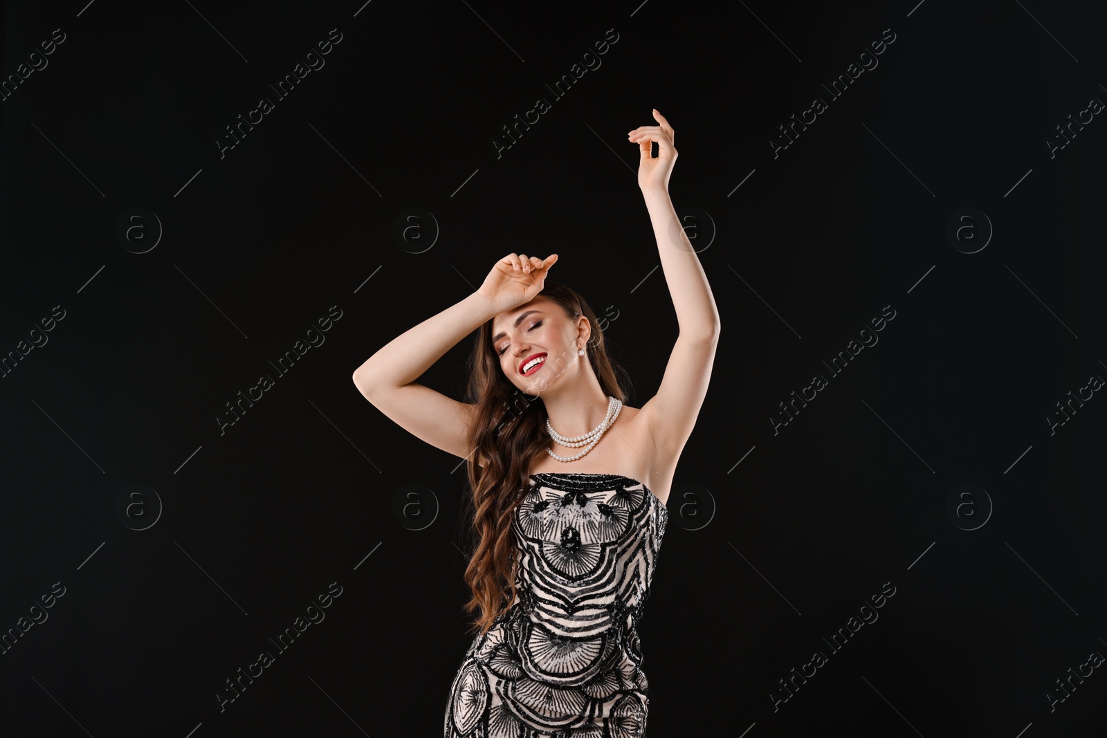 Photo of Portrait of smiling woman dancing on black background