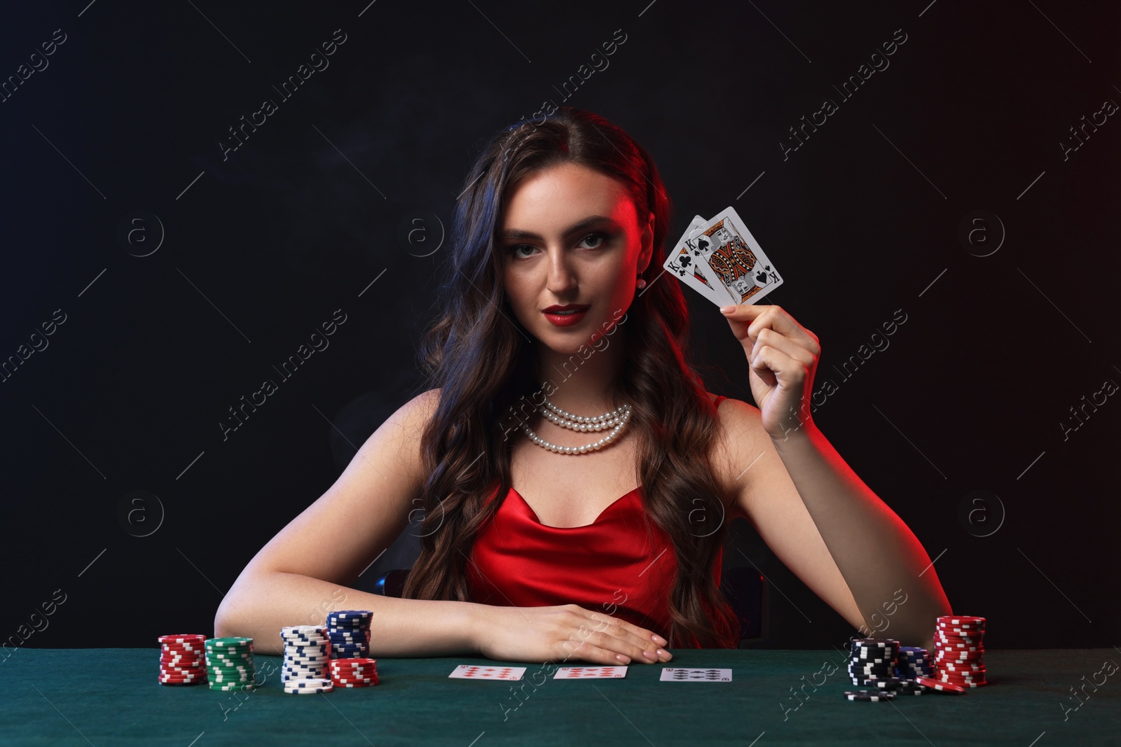 Photo of Charming woman playing poker at table on black background