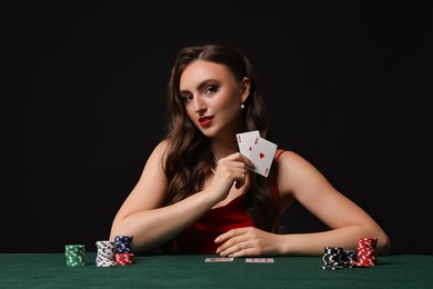 Photo of Charming woman playing poker at table on black background