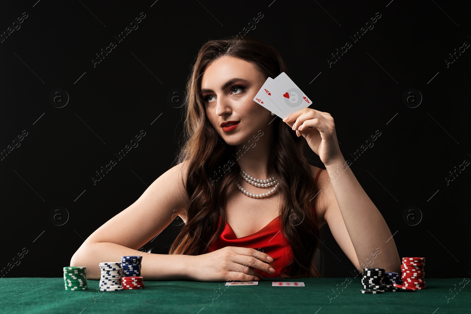 Photo of Charming woman playing poker at table on black background