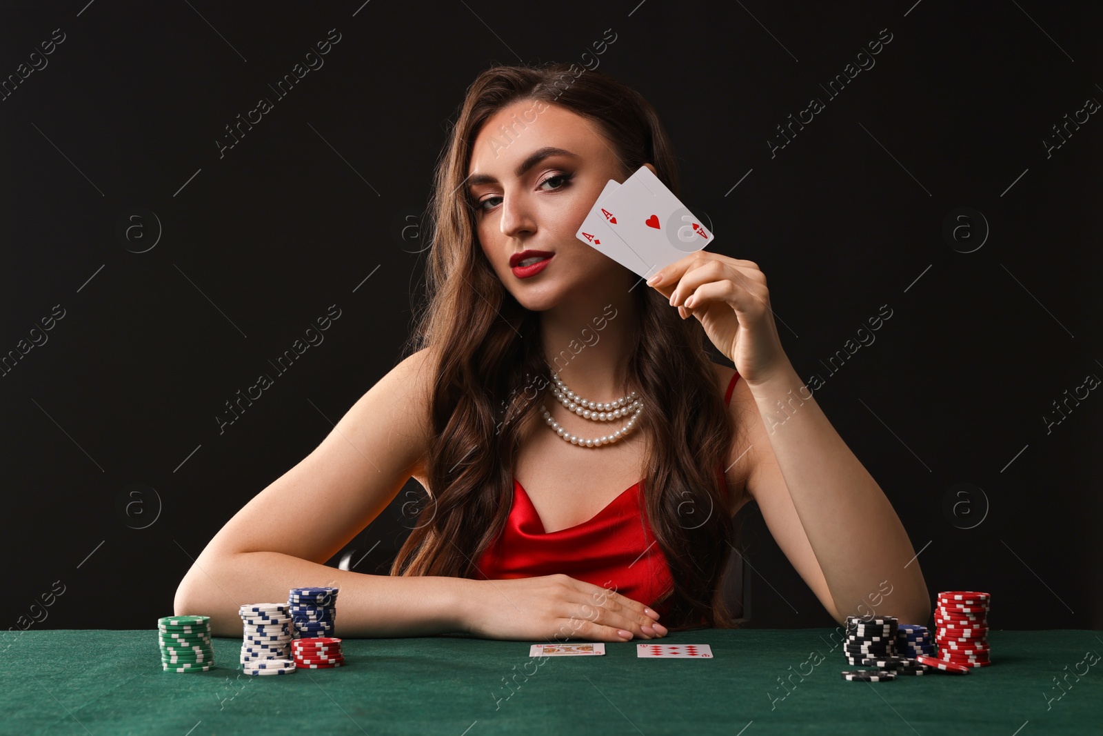 Photo of Charming woman playing poker at table on black background