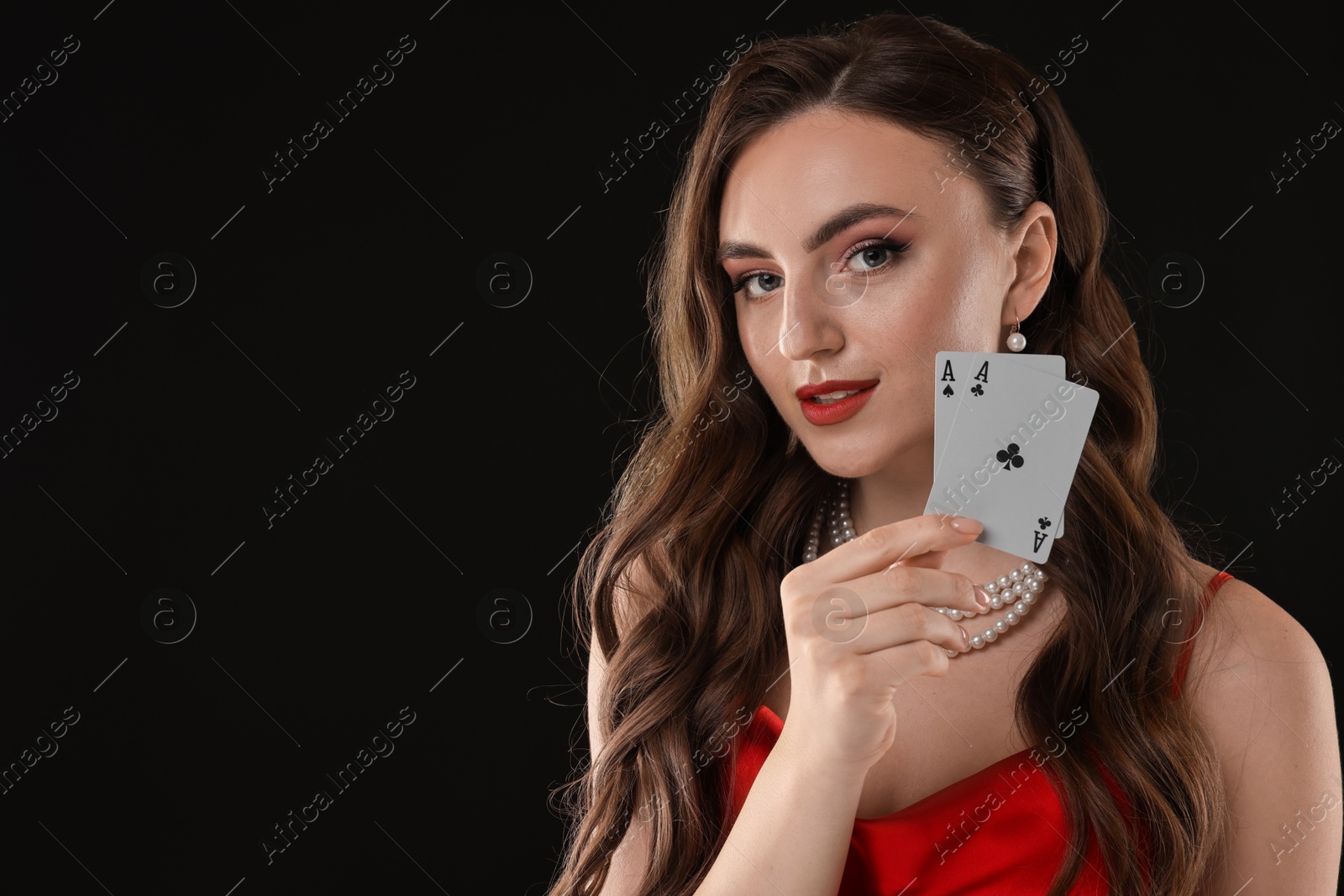 Photo of Poker game. Charming woman with playing cards on black background. Space for text