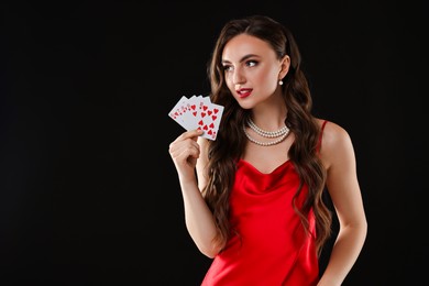 Photo of Poker game. Charming woman with playing cards on black background. Space for text