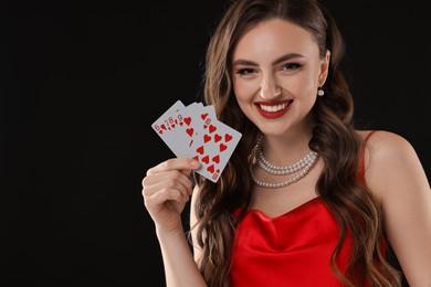 Photo of Poker game. Smiling woman with playing cards on black background. Space for text