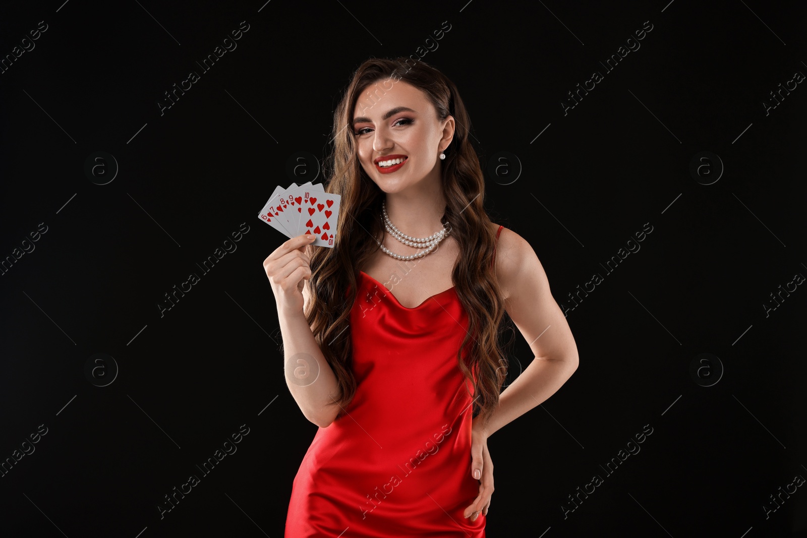 Photo of Poker game. Smiling woman with playing cards on black background