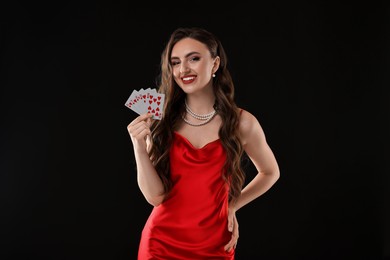 Photo of Poker game. Smiling woman with playing cards on black background