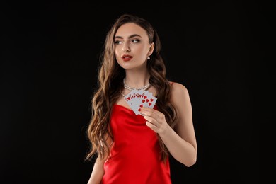 Photo of Poker game. Charming woman with playing cards on black background