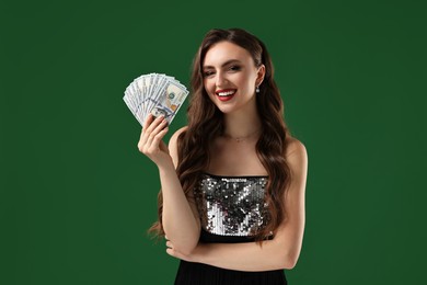 Smiling woman with dollar banknotes on green background