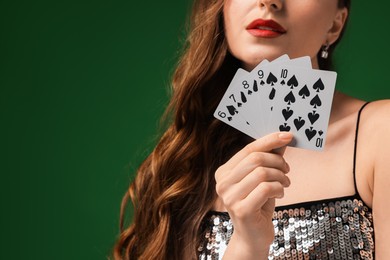 Poker game. Woman with playing cards on green background, closeup. Space for text