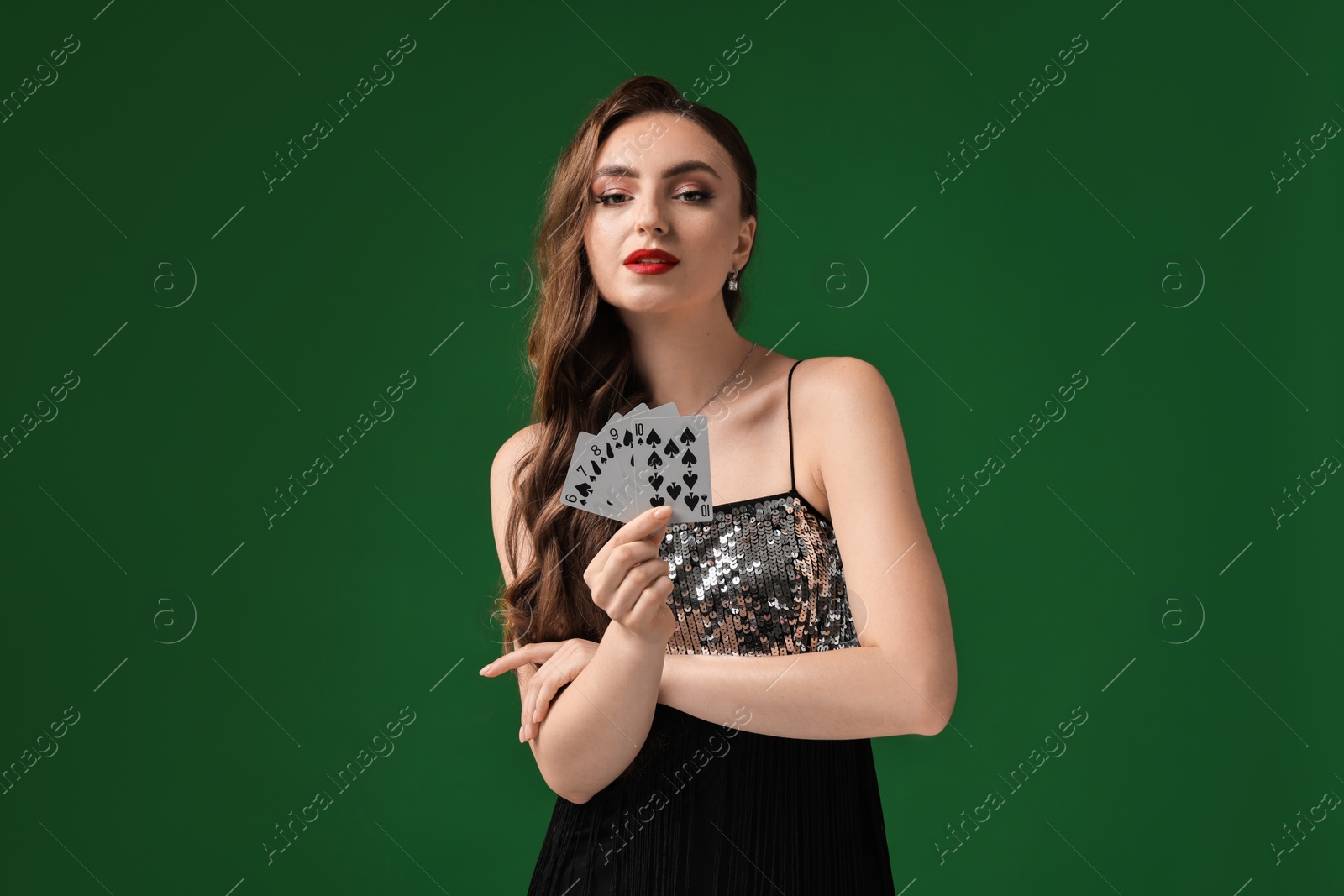 Photo of Poker game. Charming woman with playing cards on green background