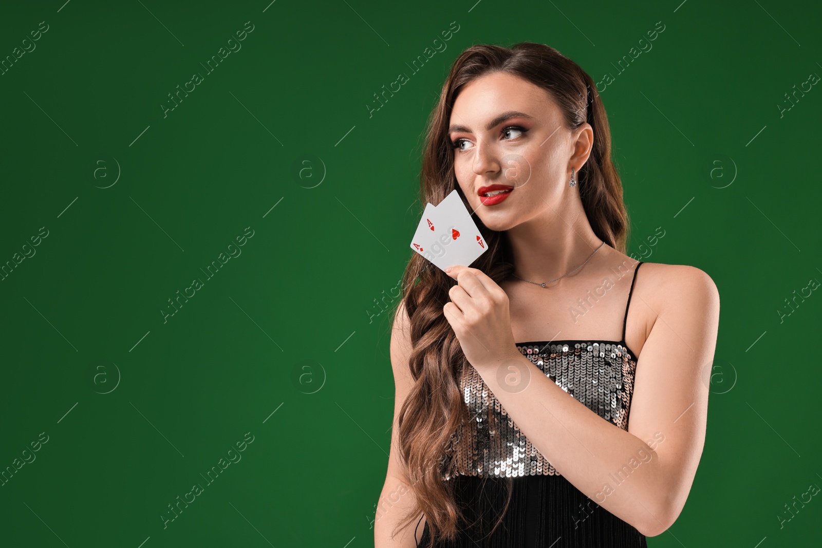 Photo of Poker game. Charming woman with playing cards on green background. Space for text