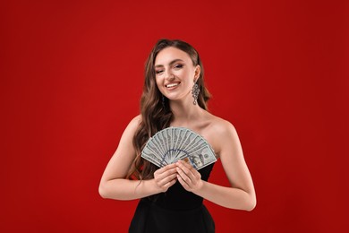 Smiling woman with dollar banknotes on red background