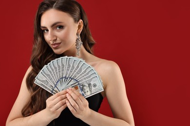 Charming woman with dollar banknotes on red background. Space for text