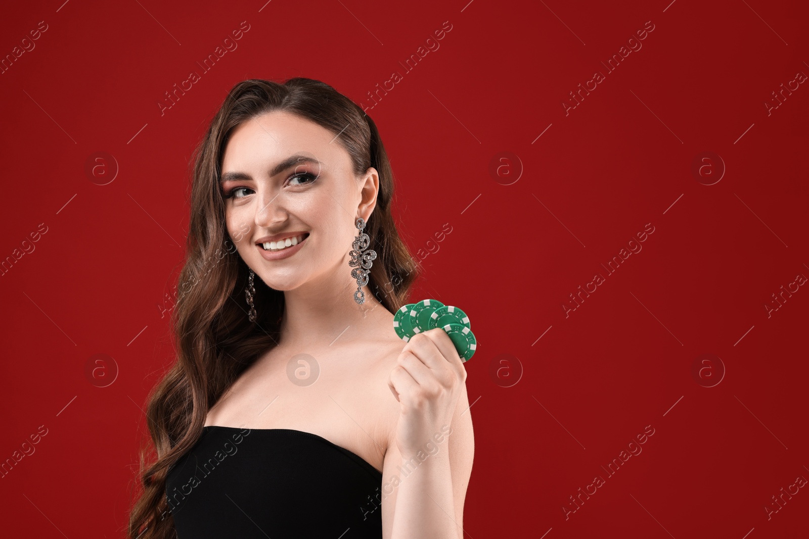 Photo of Smiling woman with poker chips on red background. Space for text