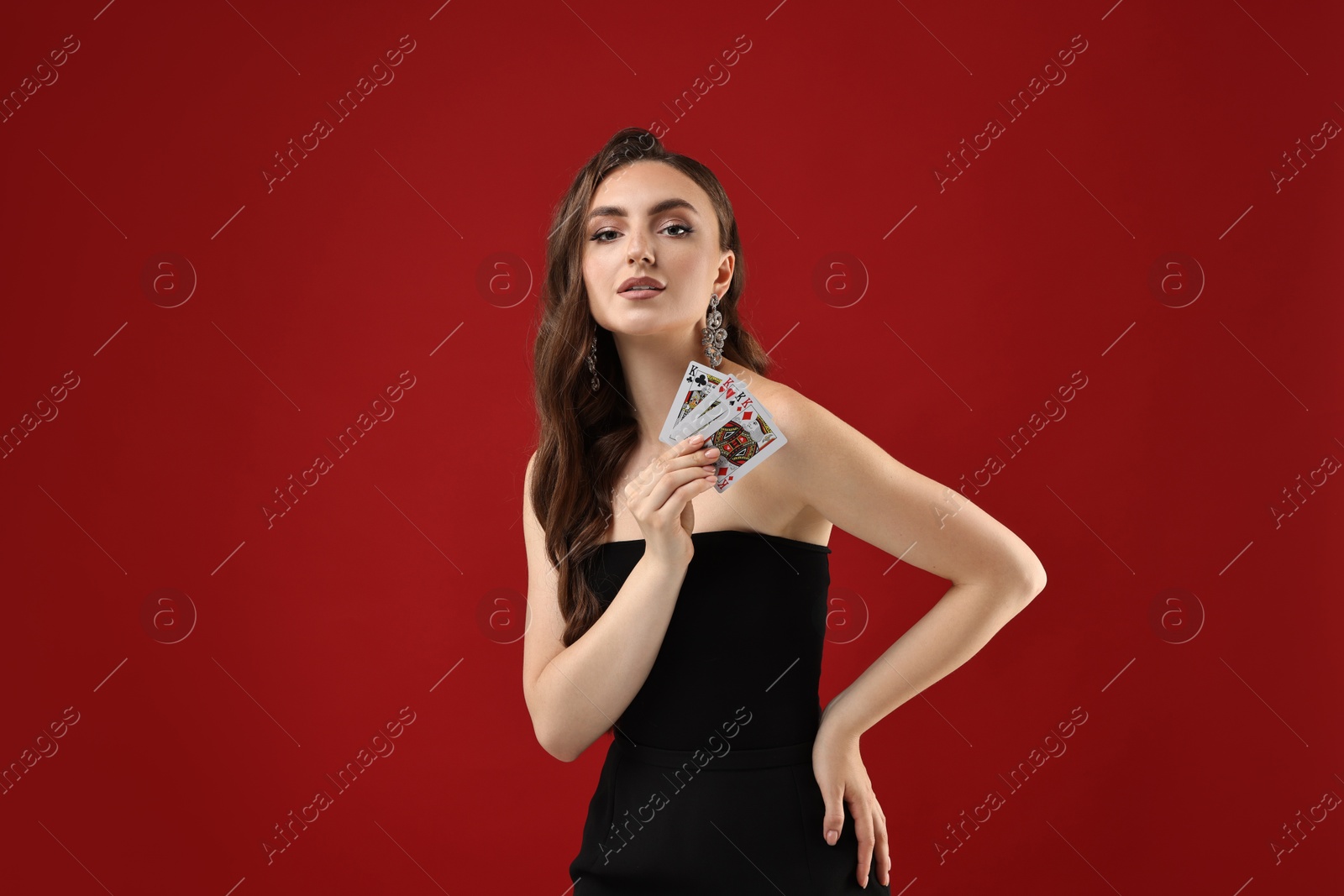 Photo of Poker game. Charming woman with playing cards on red background