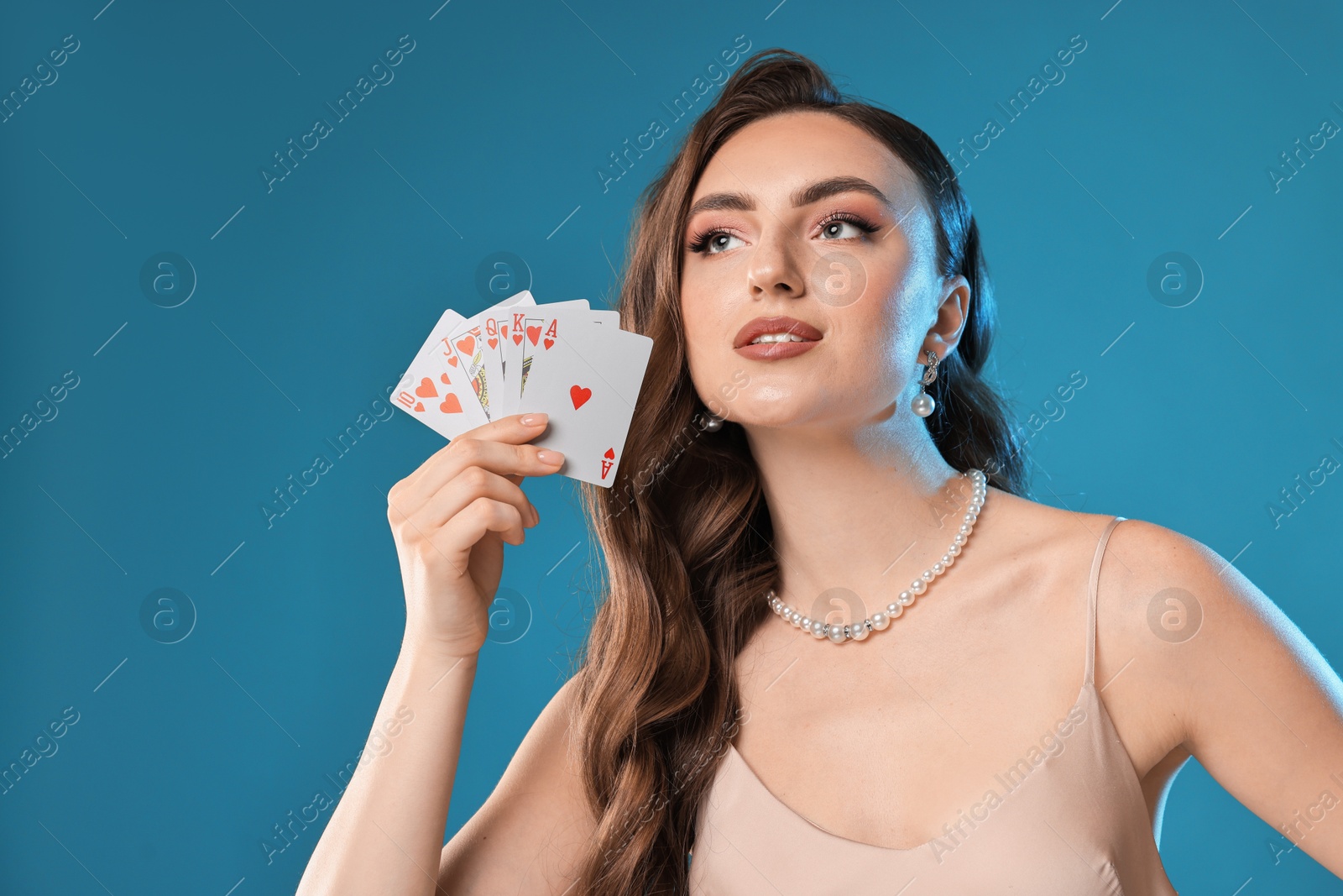 Photo of Poker game. Charming woman with playing cards on light blue background