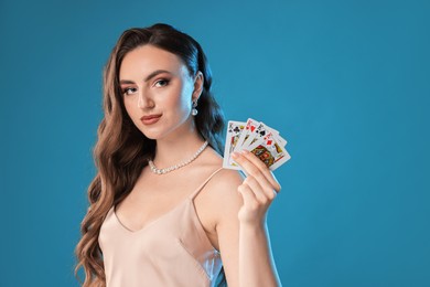 Poker game. Charming woman with playing cards on light blue background. Space for text