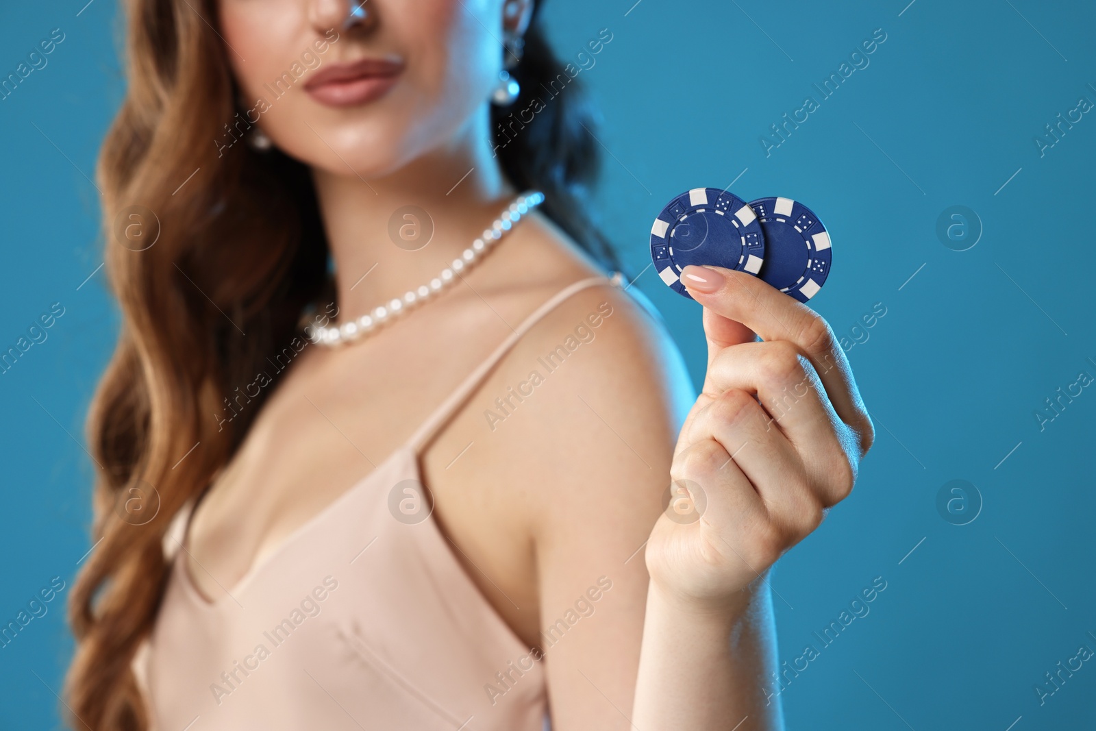 Photo of Woman with poker chips on light blue background, closeup