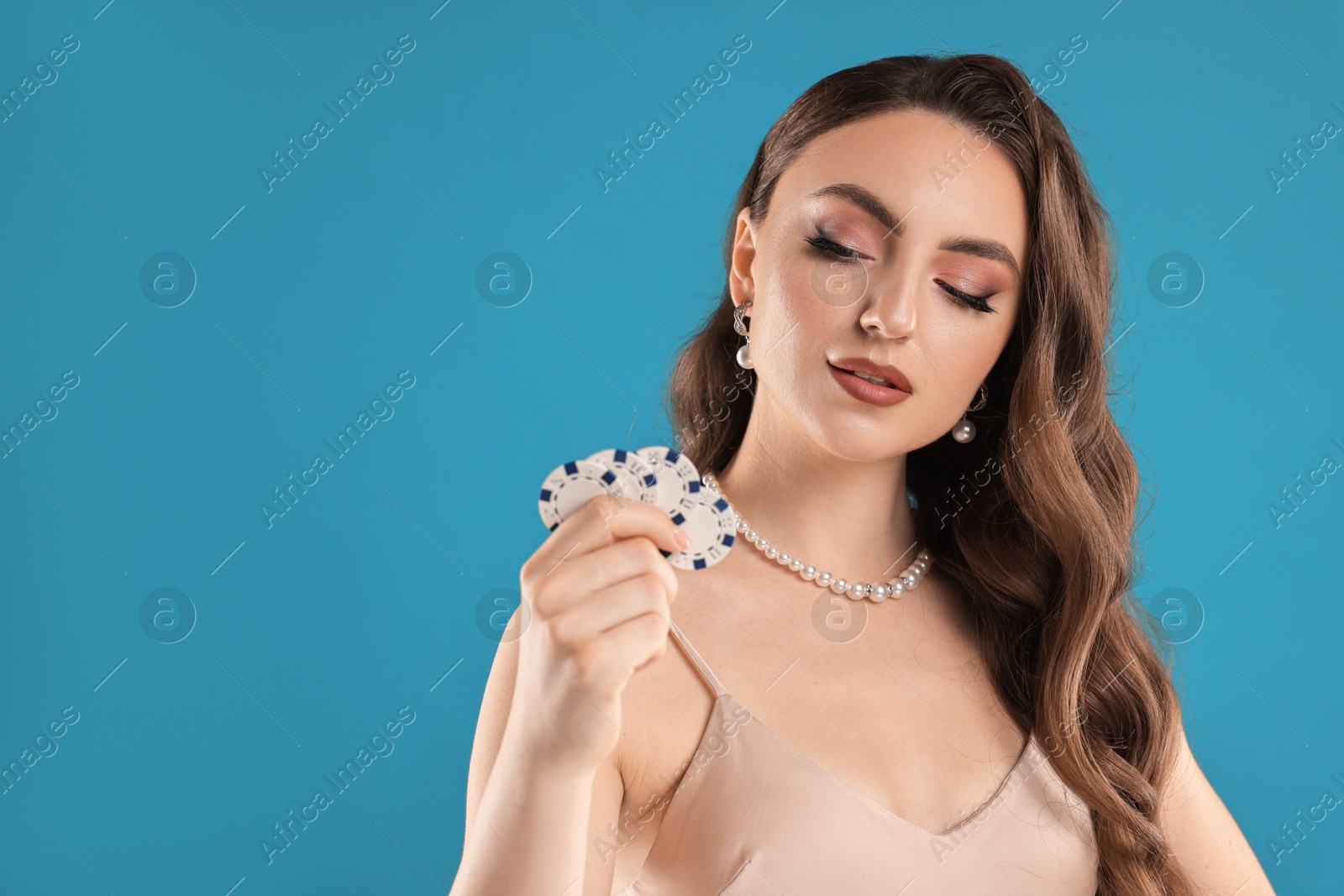 Photo of Charming woman with poker chips on light blue background. Space for text