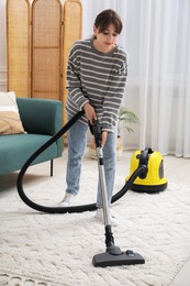 Young woman cleaning carpet with vacuum in living room